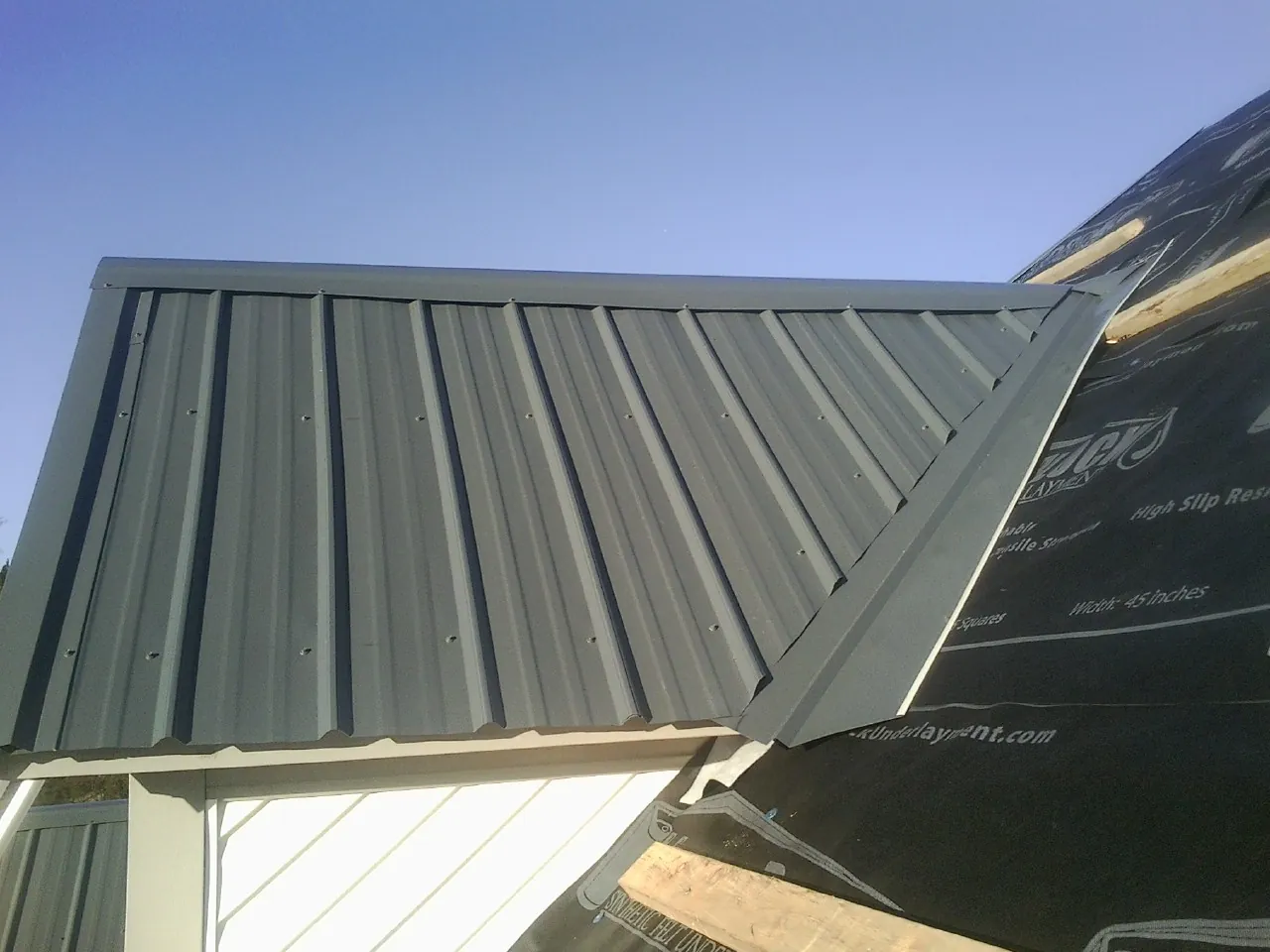 Gray metal roof panels going on over a garage gable in Port Ewen