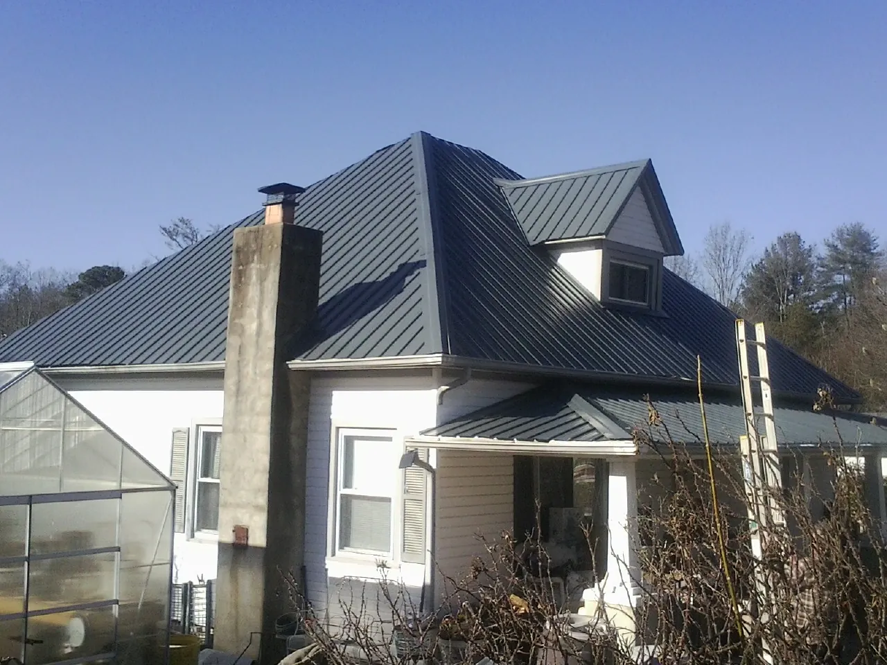 Dark blue standing seam metal roof on a white farmhouse with dormer — Slate & Tile Roof Repair by Roofing Brothers in Port Ewen