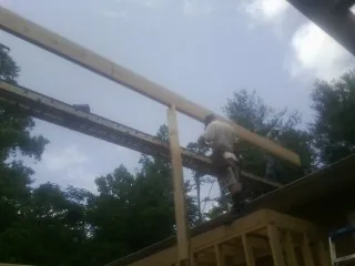 Carpenter setting a ridge beam over a new addition frame — Ice Dam Removal by Roofing Brothers in Port Ewen