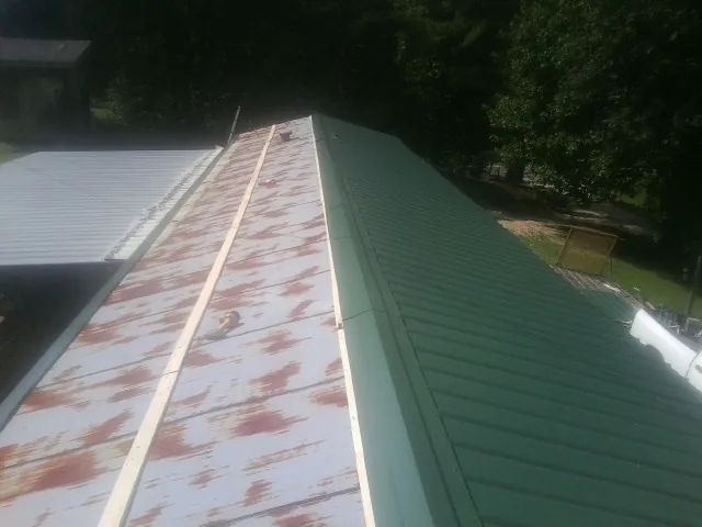 Old rusted panels beside newly installed green metal roofing — Wind Damage Roof Repair by Roofing Brothers in Port Ewen