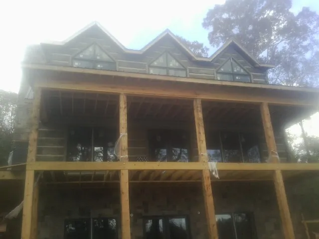 Dormers and porch framing on a large log home under construction — Roof Coating work by our crew in Port Ewen