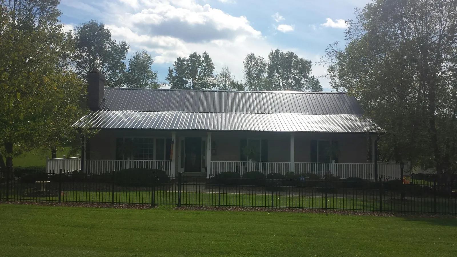 Gray metal roof on a brick ranch with a full width front porch — Gutter Guard Installation work by our crew in Port Ewen