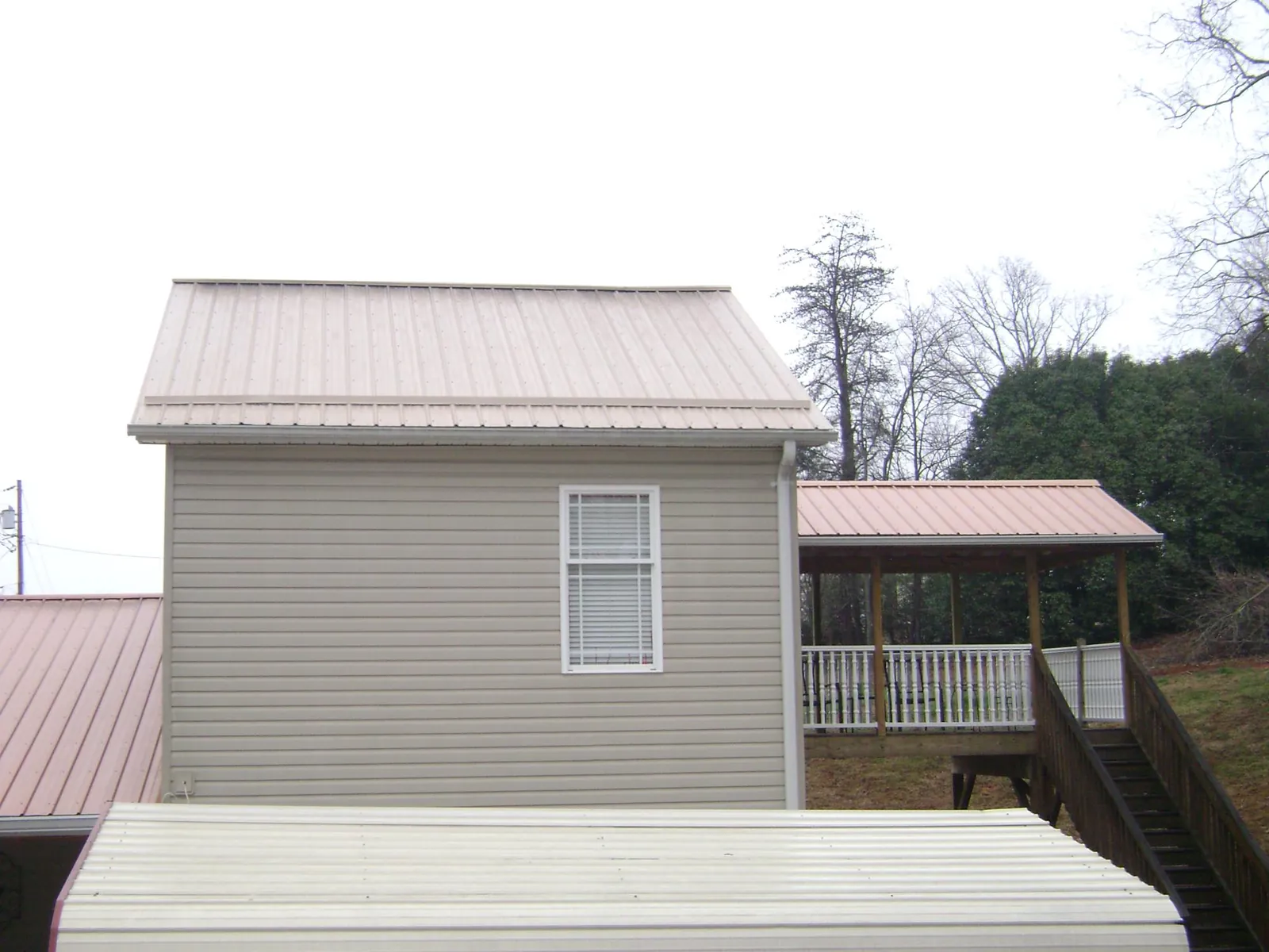 Tan metal roofs on a two story addition and attached porch, from a Roof Replacement job in Port Ewen