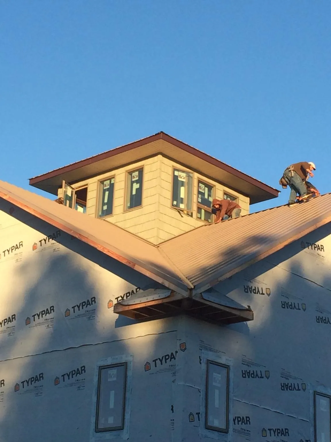 Roofers working around a rooftop cupola on a new metal roof at sunset — Roof Waterproofing in Port Ewen by Roofing Brothers